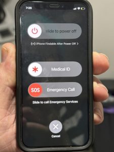 A mobile phone being held and displaying lock screen options for turning the phone off, medical information, and making an emergency call.